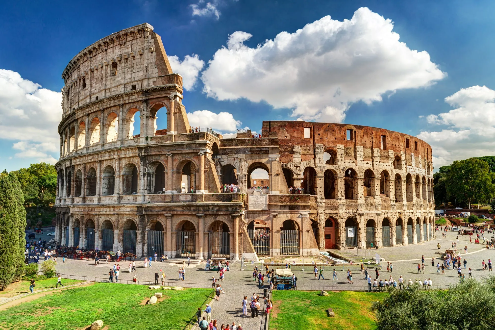The Colosseum in Rome under a blue sky with white clouds